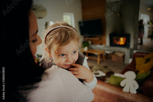 Portrait of cute little girl relaxing in mothers arms at home