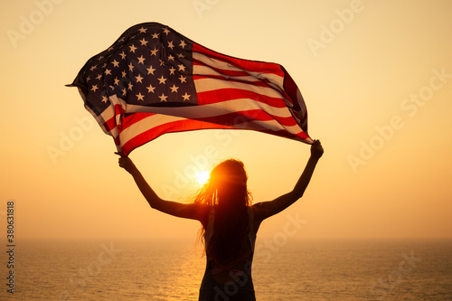 woman holding USA flag and looking at sunrice