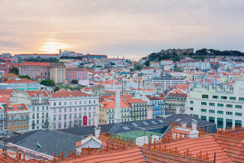 View of beautiful and colourful houses from above during sunrise with orange and pink sky in Lisbon, Portugal.