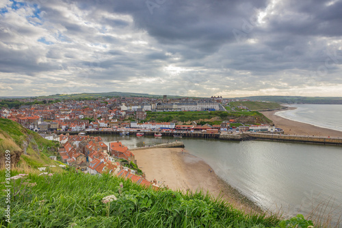 View of Whitby beach town in England with beautiful red roofs in a cloudy day.