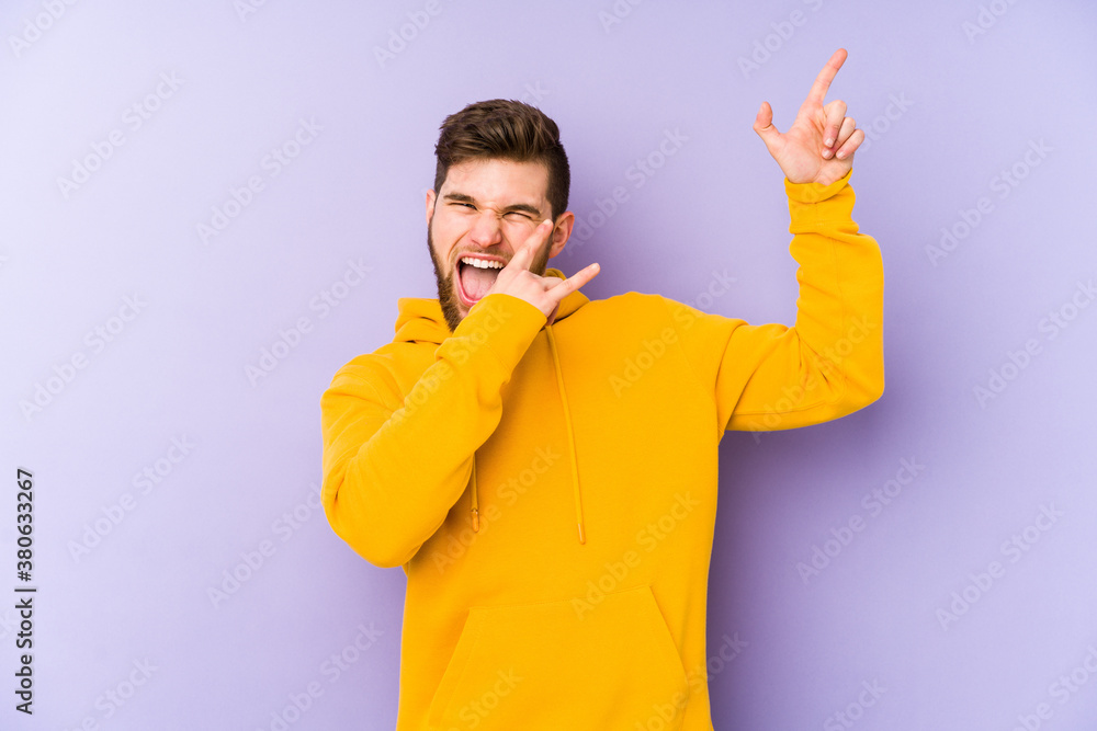 Young man isolated on purple background dancing and having fun.