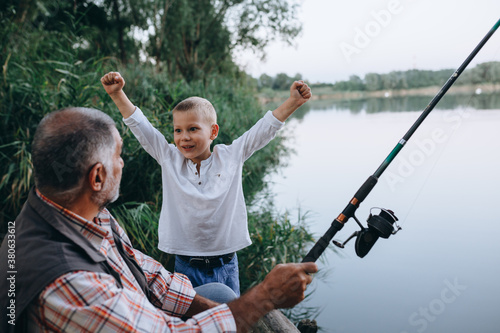 boy fishing with his grandfather outdoors at the lake