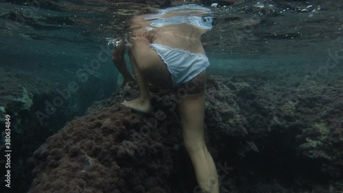 underwater footage woman on top of a rock walks out the water in the mediterranean sea photo