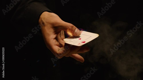 Close-up of a Magician Hand Performing Card Trick . Burning card on black Background with smoke . Card Mechanic rotating flaming jack card in hand . Shot on ARRI Alexa cinema camera in Slow Motion
