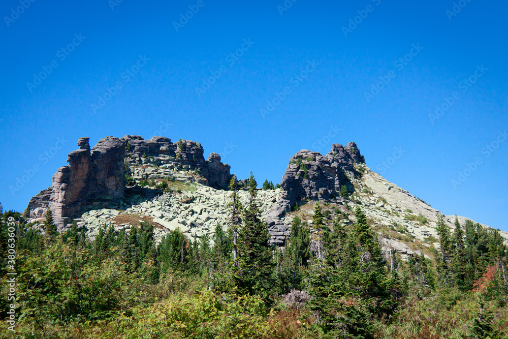 Mountains and Rocks in Siberian area Sheregesh (Russia) covered with coniferous forest on a summer sunny day