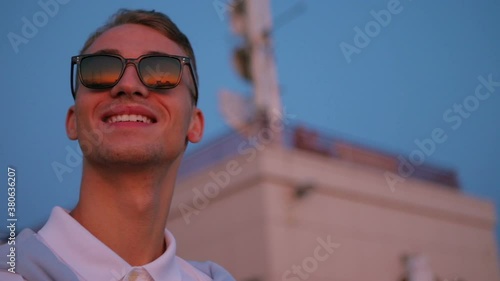 excited guy in black sunglasses admires orange sunset with cheerful smile in summer evening slow motion closeup