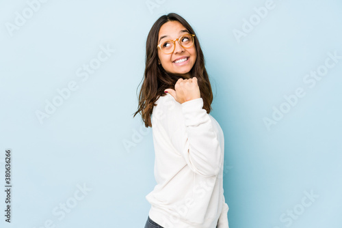 Young mixed race hispanic woman isolated points with thumb finger away, laughing and carefree.