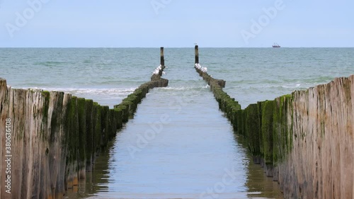 Beautiful reflection between wooden poles, wavebreakers in the netherlands with high tide. HDR photo