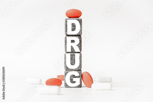 a group of white and red pills and cubes with the word drug on them, white background. Concept carehealth, treatment, therapy. photo