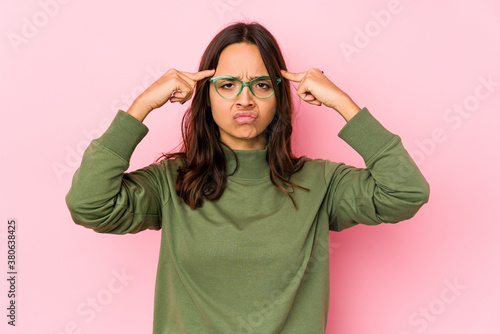 Young mixed race hispanic woman isolated focused on a task, keeping forefingers pointing head. © Asier