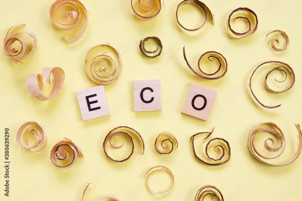 Curled shavings and word eco on yellow. Eco toys. Save the forests, awareness concept. Environmentally friendly investments. Sawdust of woodworking industry. Sawmill, carpentry Curled shavings and word eco on yellow. Eco toys. Save the forests, awareness concept. Environmentally friendly investments. Sawdust of woodworking industry. Sawmill, carpentry