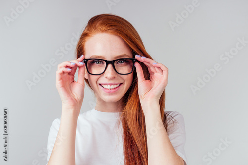redhaired ginger woman feeling happy ,wearing white cotton t-shirt in gray studio background