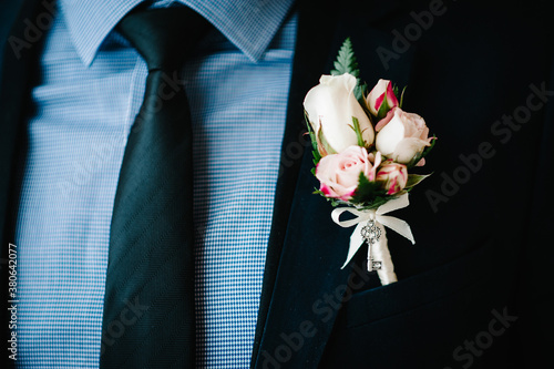 Man in a suit and tie close up. On the jacket - buttonhole, boutonniere. Morning preparation groom at home. Fashion photo of a man.