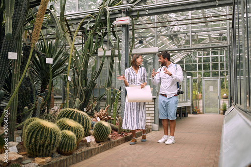 Young colleagues discussing cactuses in a botanical garden photo