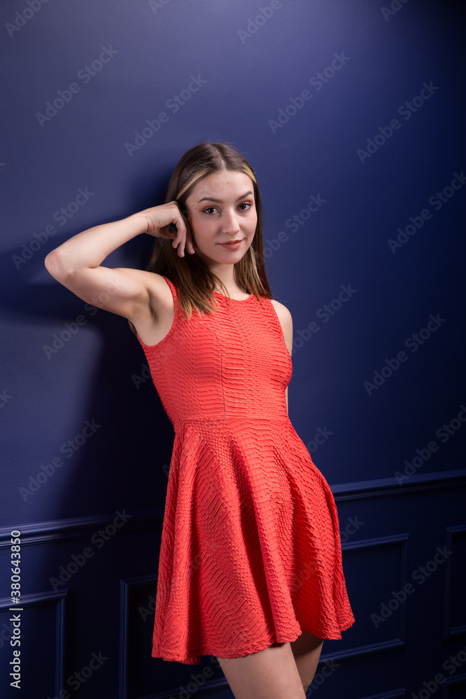 A beautiful woman in a red dress against a blue wall. A beautiful woman in a red dress against a blue wall.