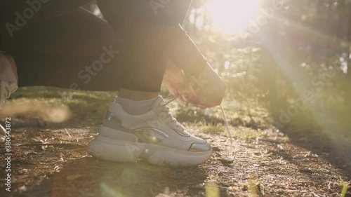 Sportswoman tying shoelaces against the background of the sun