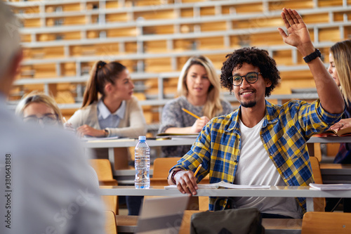 Male student raising the hand for a question at the lecture