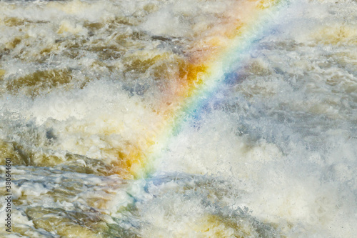 Splashing water waves with rainbow on the fast river © Elena Noeva