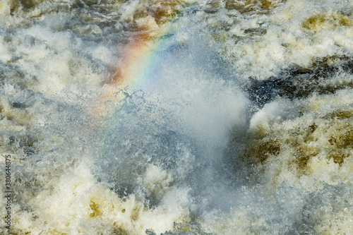 Splashing water waves with rainbow on the fast river © Elena Noeva