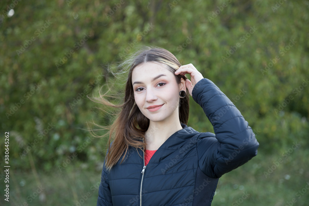 Portrait of a beautiful brunette outdoors on a green forest background.