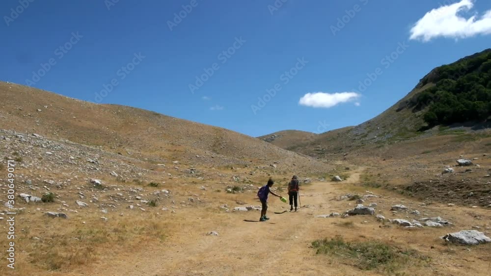 Tourists trek up a rugged hill in rural Italy on a hot, sunny day. Cammino dei Briganti trekking, Abruzzo Italy Tourists trek up a rugged hill in rural Italy on a hot, sunny day. Cammino dei Briganti trekking, Abruzzo Italy