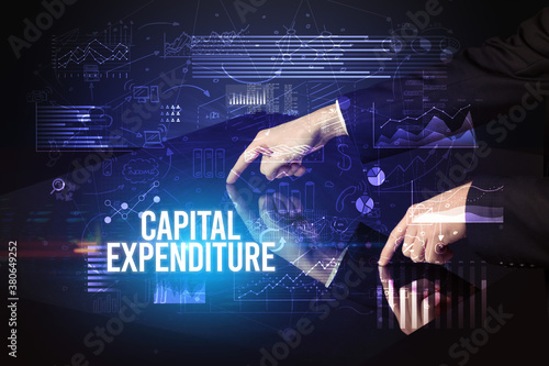 Businessman touching huge screen with CAPITAL EXPENDITURE inscription, cyber business concept