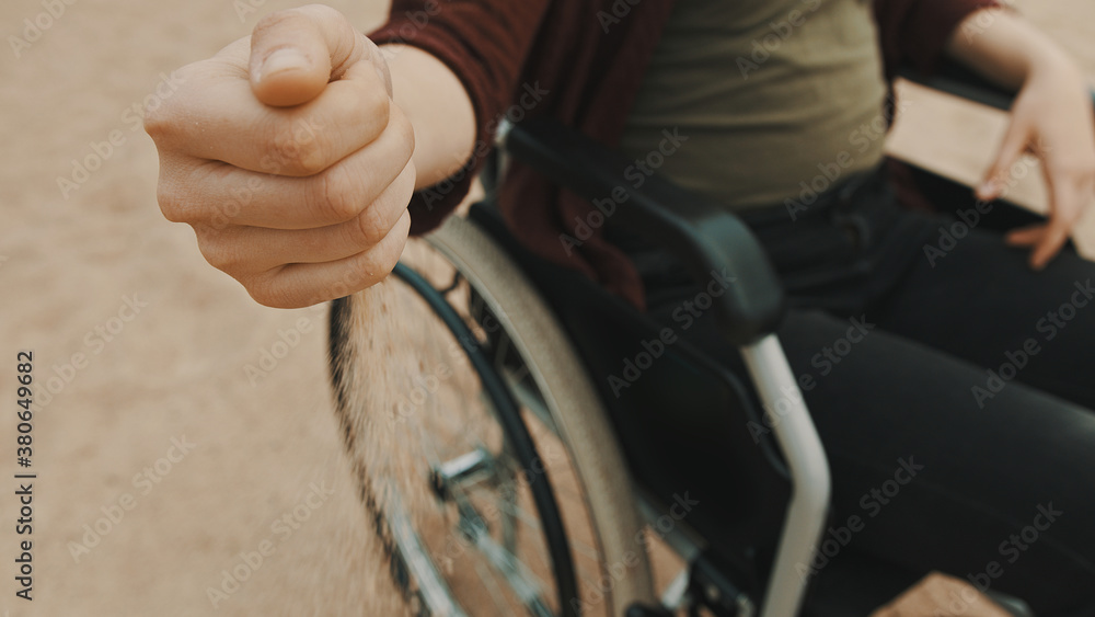 close up, hand of disabled person in the wheelchair playing with the sand on the beach. High quality photo