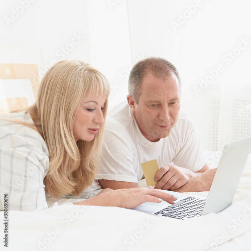 Mature family couple looking at laptop screen. Happy middle aged man holding credit card and female making purchases online. Preparing for travel, planning vacation, booking ticket
