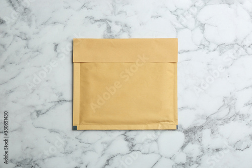 Kraft paper envelope on white marble background, top view