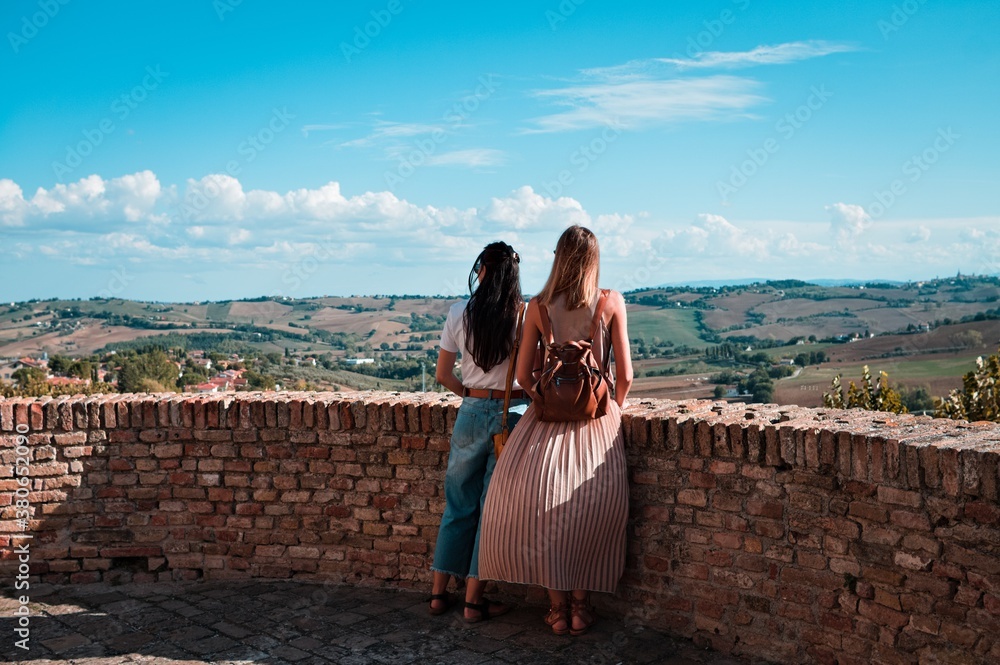 A couple of women is looking the panoramic view of the italian hills from a medieval tower (Corinaldo, Marche, Italy, Europe)