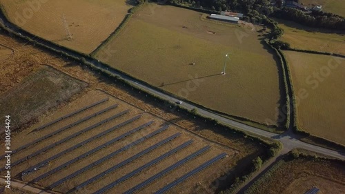 Flying Over Sunny Fields with Solar Panels and Wind Turbine - 4K Aerial Footage photo