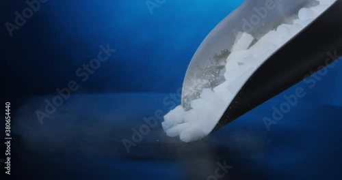 Dropping a scoop of dry ice pellets on black table in slow motion with RED camera