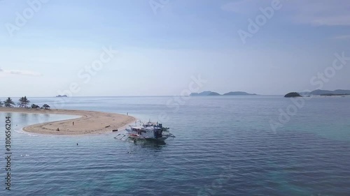 Rotating aerial shot of a boat docked on a sandbar of a small remote island in the middle of an ocean on a summer day photo