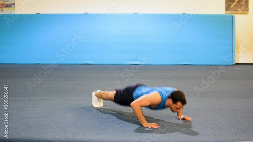 a guy doing a special kind of push up
in a top/side/front view still shot
inside a gymnastics gym photo