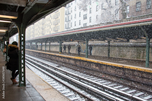 gros flocons de neige tombant sur les rails d'un gare avec des passagers attendant sur les quais 