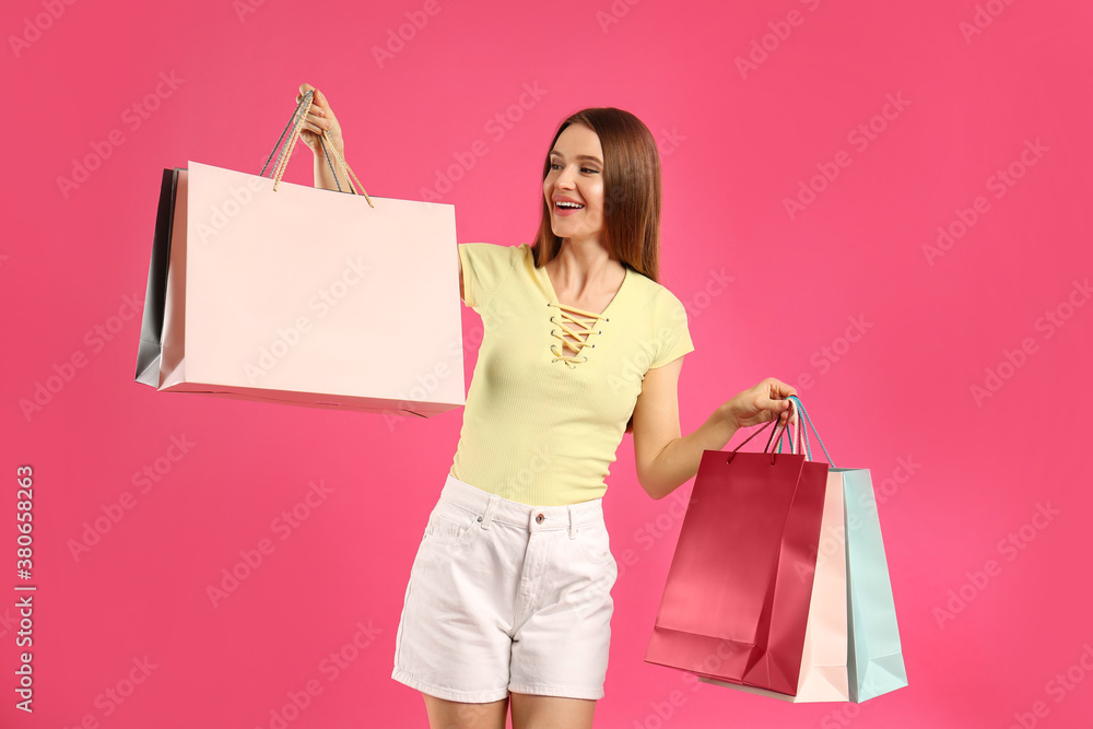 Beautiful young woman with paper shopping bags on pink background Beautiful young woman with paper shopping bags on pink background