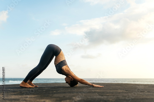 Yoga at sunset on the beach. woman performing asanas and enjoying life on the ocean. Bali Indonesia.