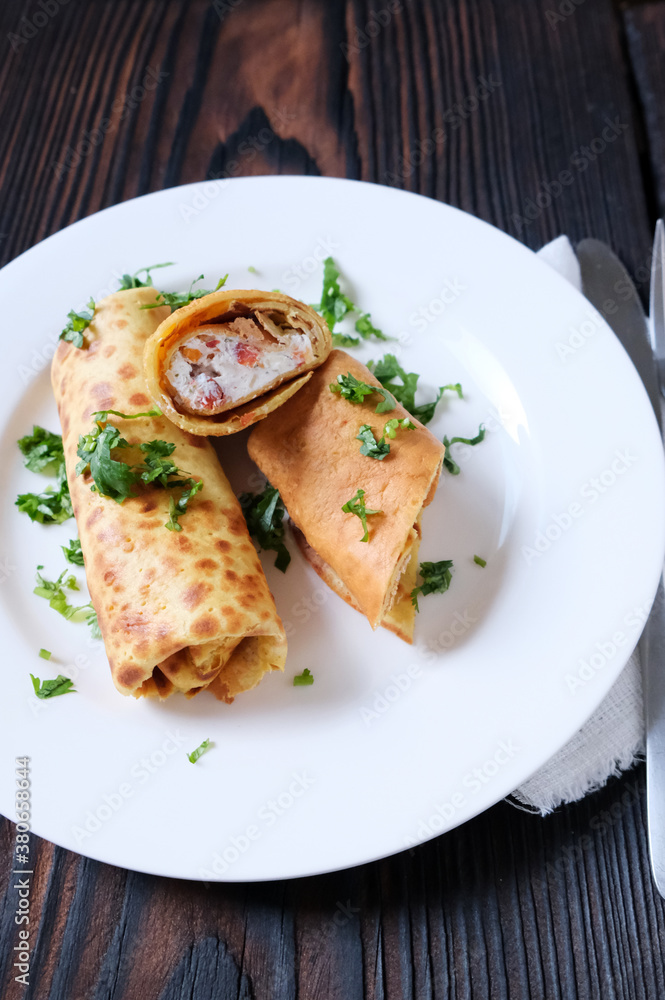 Chickpea crepes filled with feta cheese and sun-dried tomato on the white plate. Homemade traditional breakfast. Chickpea crepes filled with feta cheese and sun-dried tomato on the white plate. Homemade traditional breakfast.