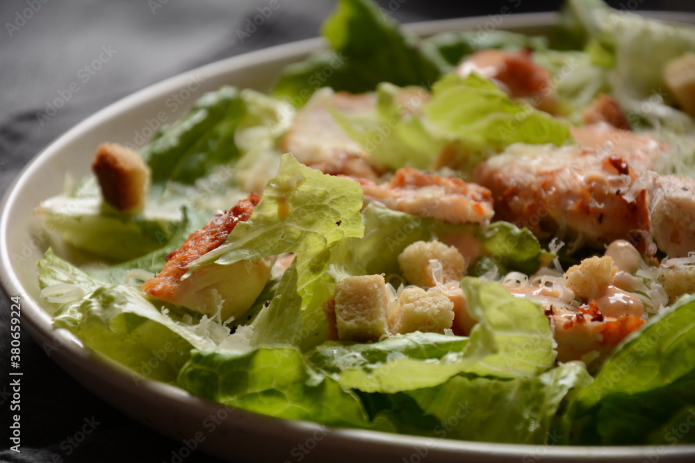 Caesar Salad with grilled chicken, Cheese and Croutons with lettuce, on plate. Grilled chicken breasts and fresh vegetables in plate. Caesar Salad with grilled chicken, Cheese and Croutons with lettuce, on plate. Grilled chicken breasts and fresh vegetables in plate.