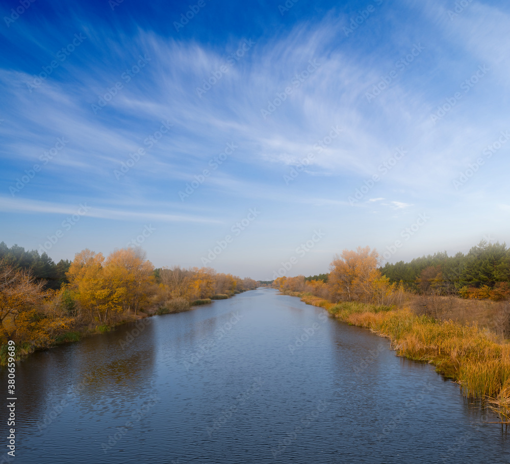 irrigation channel with red forest on a coast, autumn river scene