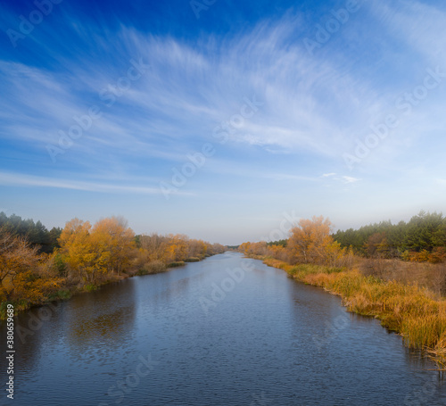 irrigation channel with red forest on a coast, autumn river scene