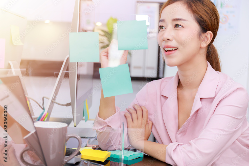Close up business start up successful smile woman writing note on post-it at office. Businesswoman brainstorm writing note on blue post note and sticky note. Close up business start up successful smile woman writing note on post-it at office. Businesswoman brainstorm writing note on blue post note and sticky note.