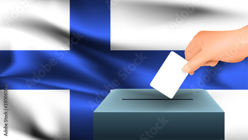 Male hand puts down a white sheet of paper with a mark as a symbol of a ballot paper against the background of the Finland flag. Finland the symbol of elections