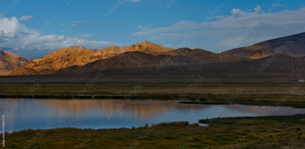 Central Asia. Tajikistan. A picturesque lake with swampy shores in a deserted mountain valley along the Pamir highway. Central Asia. Tajikistan. A picturesque lake with swampy shores in a deserted mountain valley along the Pamir highway.
