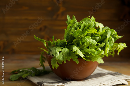 Fresh arugula in bowl on wooden table