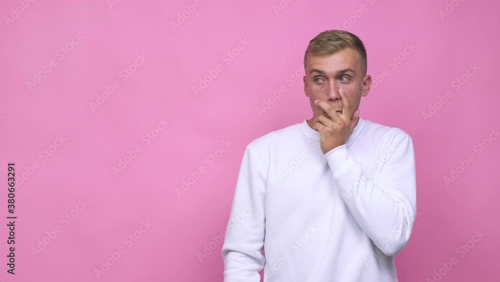 Young caucasian man thoughtful looking to a copy space covering mouth with hand Young caucasian man thoughtful looking to a copy space covering mouth with hand