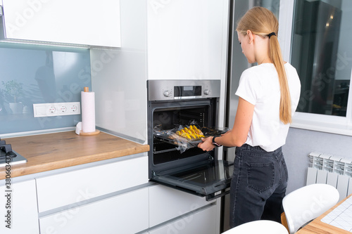 Beautiful young woman baking in the oven in the kitchen