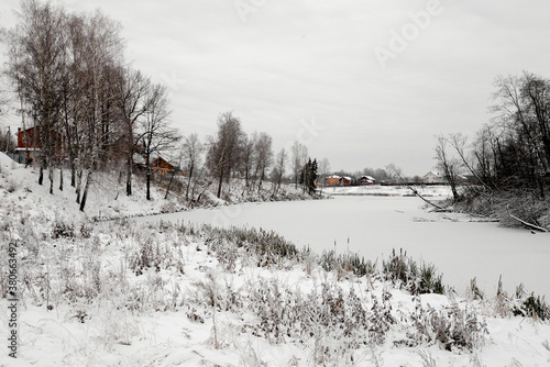 landscape with snow covered houses and pond