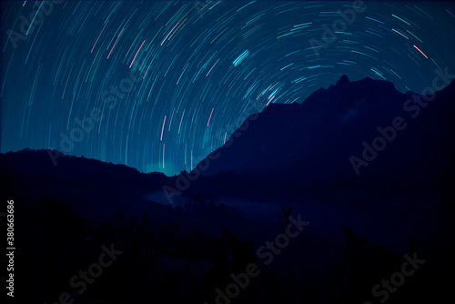 Night landscape with stars above mountains and distant galaxies.
