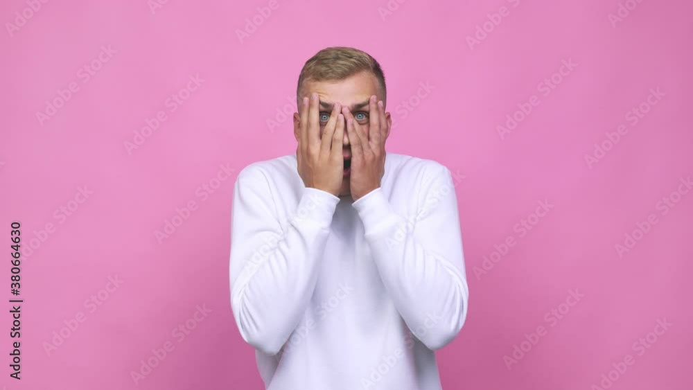 Young caucasian man blink through fingers frightened and nervous Young caucasian man blink through fingers frightened and nervous